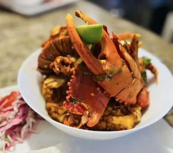 Savor crab served in a bowl garnished with lime wedges and paired with shredded red cabbage on the side during the Dinner Walking Food Tour.