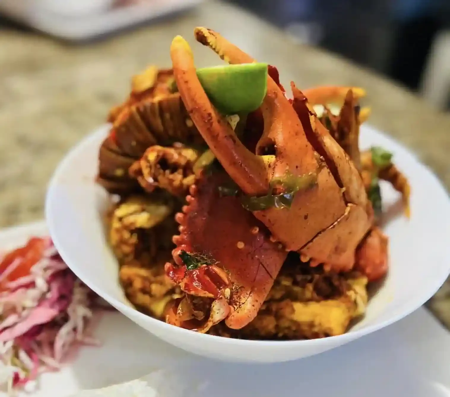 Savor crab served in a bowl garnished with lime wedges and paired with shredded red cabbage on the side during the Dinner Walking Food Tour.