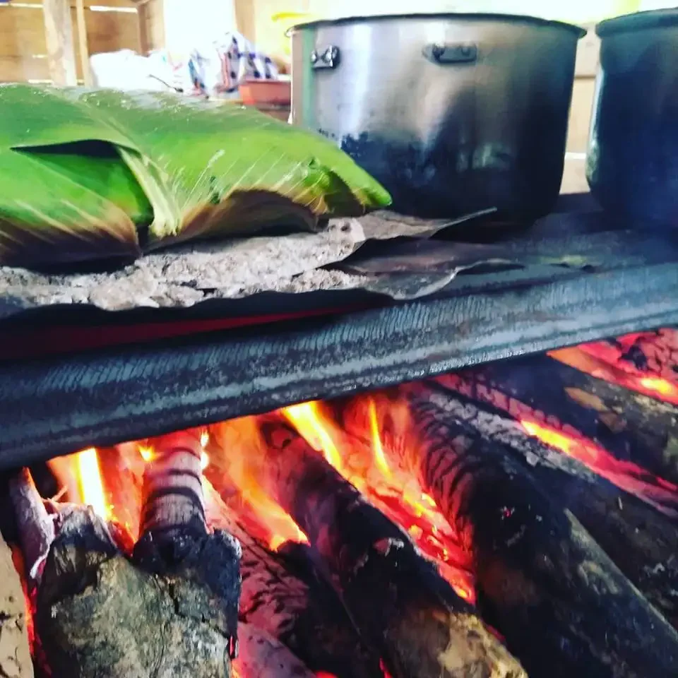 A traditional stove with open flames heats pots and a banana leaf-wrapped item during the 3 Adventures Combo Tour.