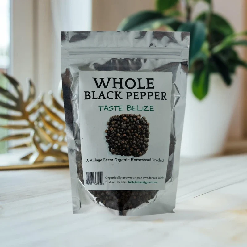 A package labeled "Import placeholder for 1135" sits on a table, indicating it's whole black pepper from an organic homestead farm in Toledo District, Belize.